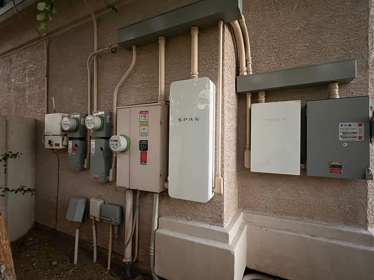 Bank of residential smart meters mounted on a stucco wall — the meters that bill electricity, gas, and sometimes water.